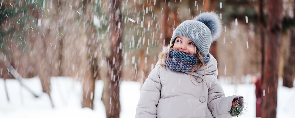 Kid outside in the winter with scarf and hat on.