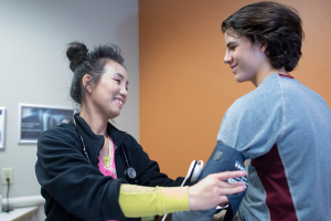 Medical assistant taking teen blood pressure