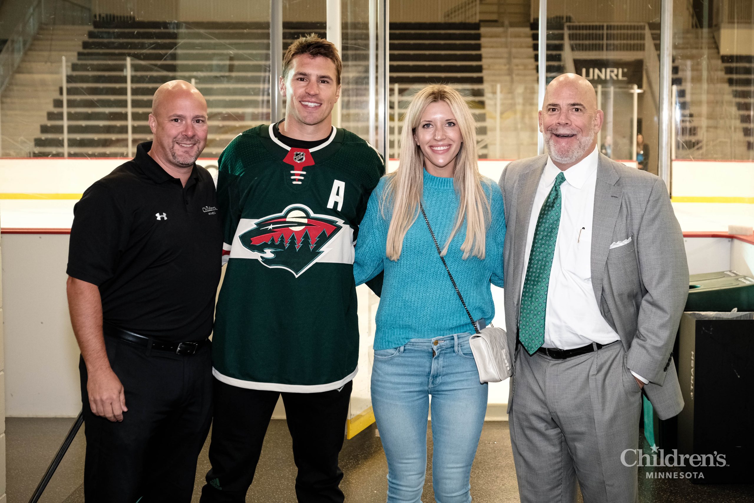 Zach, his wife and some Children's Minnesota employees smiling outside of the rink