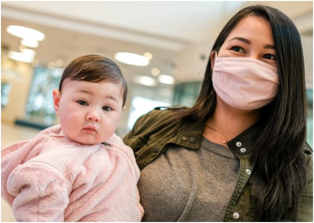 mother wearing a mask, holding her child in the hospital