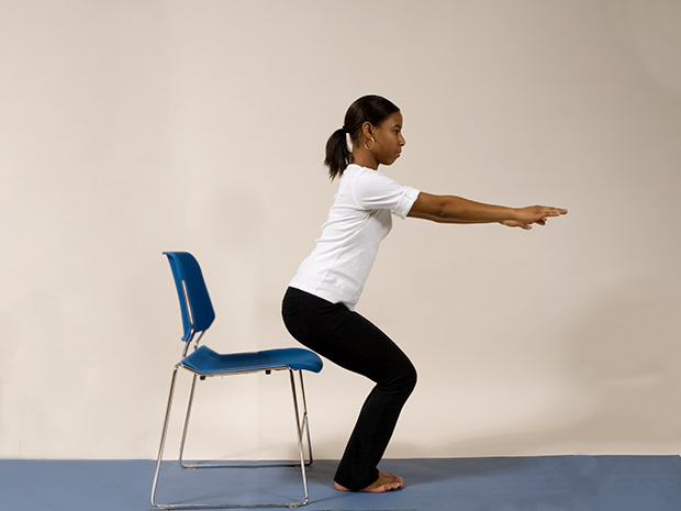 Model demonstrates step 2 of the chair squat exercise
